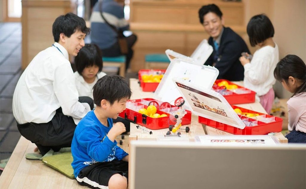 ロボット工作キットを組み立てる子どもたちと、そばで見守る講師